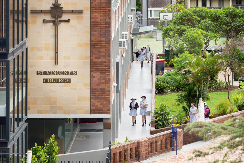 Aerial Shot of College Building with Signage and Students Walking Down Side Path